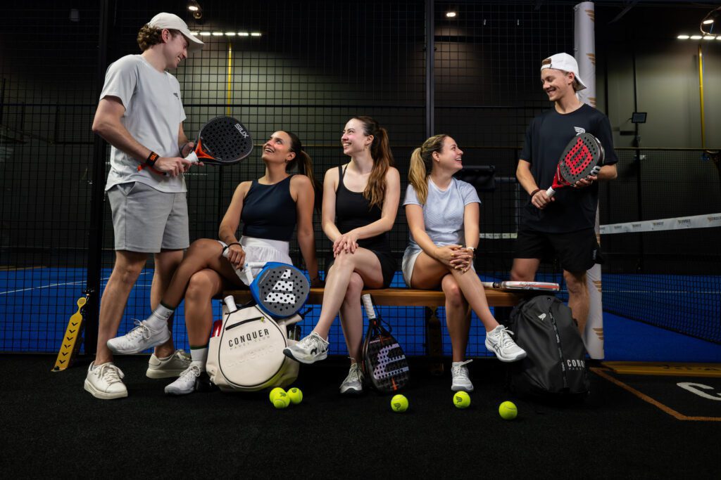 A group of friends playing inside a padel community facility.